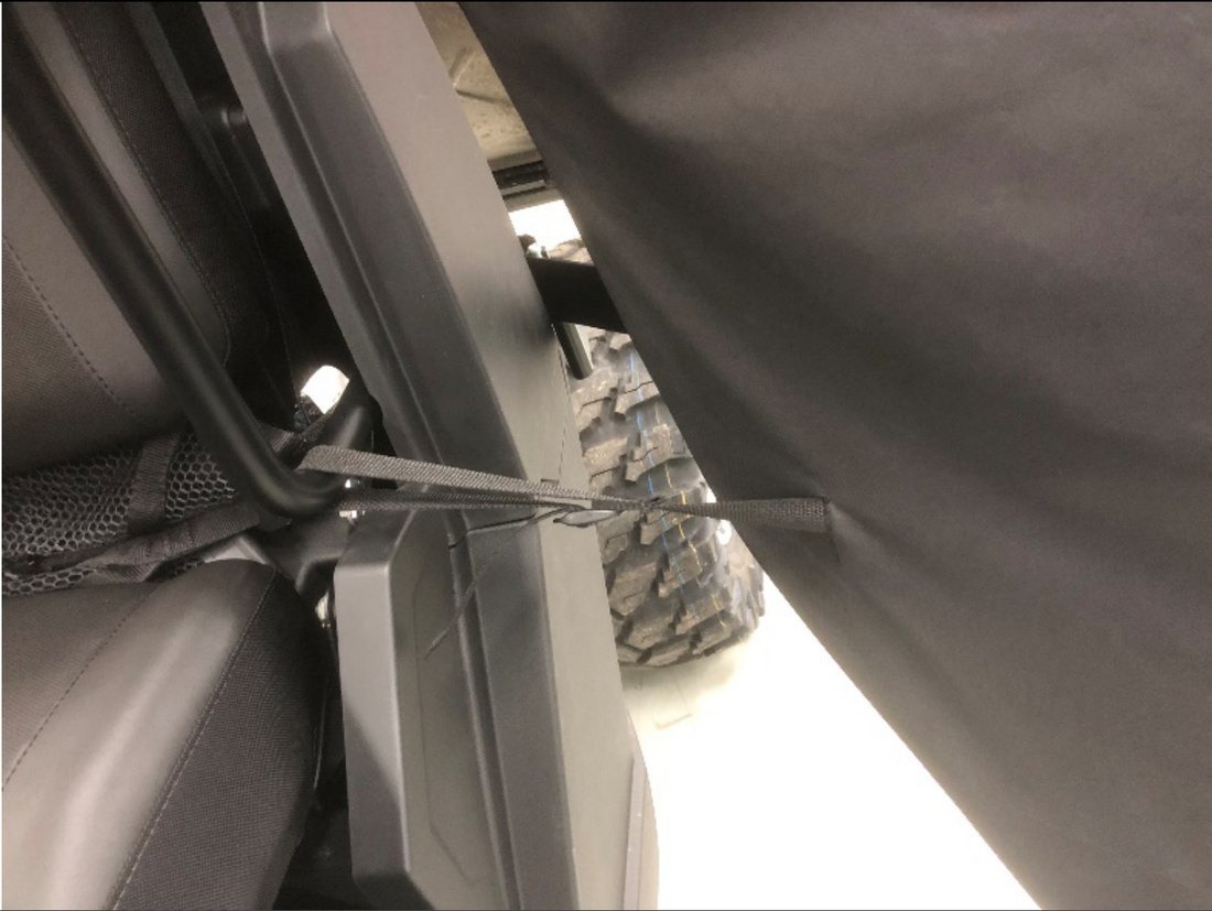 Door limiter strap routed around the lower frame tube and hip bolster